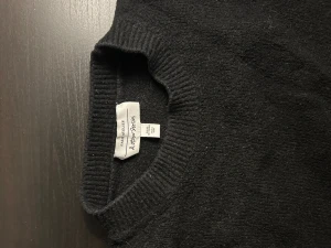 Svart stickad tröja från & Other Stories - Svart stickad tröja från & Other Stories Paris Atelier med rund hals och breda ribbade muddar vid ärmslut och nederkant. Tröjan har lång ärm och en klassisk, enkel design som är lätt att matcha med allt. Perfekt för dig som gillar stilrena plagg.