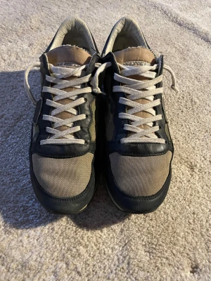 Philippe Model camo sneakers - Snygga sneakers från Philippe Model med camouflagemönster i grönt och brunt, svarta skinnpaneler och beige mesh framtill. Perfekt för dig som gillar streetstyle. De är väldigt snygga och är i ganska bra skick. Det är bara sulan som är lite trasig som man ser på bilden. Hör av dig om du undrar något😁