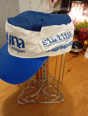 Blåvit keps Luna Verktyg Maskiner - Säljer en unik blåvit keps med tryck från Luna Verktyg Maskiner och Statin Sandviken. Kepsen har en bred blå skärm och vit front med blå text. Toppen är blå och materialet känns som bomull med plastskärm. Perfekt för dig som gillar retro och industriell stil.