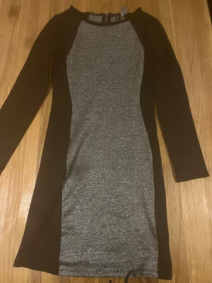 Grå och svart långärmad klänning från DIVIDED - Snygg klänning från H&M med lång ärm och figurnära passform. Gråmelerad mitt del med silver glitter melerad 