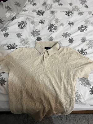 Beige kortärmad skjorta från Riley - Snygg beige skjorta från Riley med klassisk krage och korta ärmar. Skjortan har en diskret textur i tyget som ger en cool känsla. Perfekt för dig som gillar stilrena och enkla plagg. Passar dig som vill ha en neutral färg i garderoben.