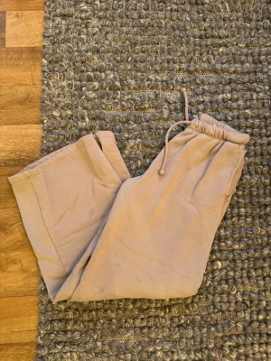 Beige mjukisbyxor från H&M XXS - Säljer ett par beige mjukisbyxor från H&M i storlek XXS. Byxorna har breda ben, resår i midjan med snörning och är gjorda i mjukt bomullsmaterial. Perfekta för chill dagar och har en loose passform som ger en avslappnad vibe.