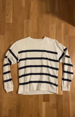 Randig tröja - En vit lite tjockare tröja med marinblå ränder, slit längst ner på båda sidorna av tröjan. 