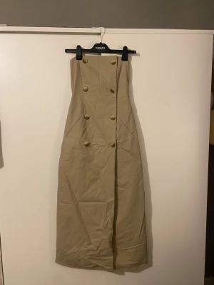 Bandauklänning från NA-KD - Maxiklänning i bandau. Silikonremsa på framsidan,  resår i ryggen och dragkedja i sidan. Upplever den lite lite stor i storleken och den kommer därför inte till användning 