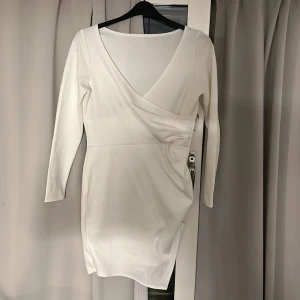 Vit omlottklänning med lång ärm - Ävit kortklänning med omlottdetalj och v-ringning. Strl L men liten i strl
