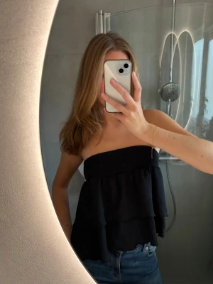 Svart volankjol/volangtopp/bandeautopp - Svart kort volangkjol från Gina Tricot men som jag använt som bandeautopp, passar superfint som båda och!! Mycket bra skick. Storlek S💗