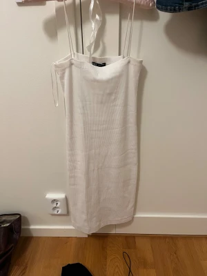 Vit ribbad klänning från Zara - Säljer en vit ribbad klänning från Zara i storlek M. Klänningen är ärmlös med tunna axelband och har en rak, kroppsnära passform som slutar ovanför knäna. Perfekt för en clean och stilren look.