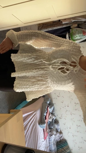 Vit omlott blus med snörning - Säljer en vit blus med långärmad design och snygg snörning framtill. Blusen har en omlott-look och är tillverkad i ett krusigt, texturerat material som ger en cool och unik känsla. Perfekt för dig som gillar detaljer och vill sticka ut. Från Gina