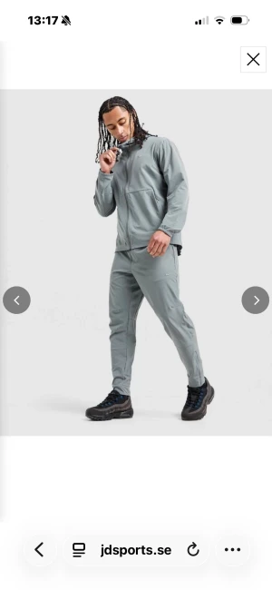 Grå träningsset från Nike - Snyggt grått träningsset från Nike med matchande jacka och byxor. Jackan har dragkedja framtill och två fickor, medan byxorna har smal passform och diskret Nike-logga. Perfekt för gymmet eller sportaktiviteter.