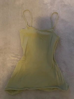 Ljusgrön linnetopp med smala axelband - Säljer en ljusgrön linnetopp med smala axelband och enkel, rak design. Toppen är ärmlös och har en mjuk, stretchig känsla i materialet. Perfekt för varma dagar och enkel att matcha med jeans eller kjol. Färgen är fräsch och passar dig som gillar minimalistisk stil.