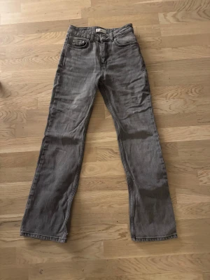 Grå jeans - Grå utsvängda jeans från Gina Tricot. Storlek 32. Innerbenslängden är ca 74cm. Bra skick.