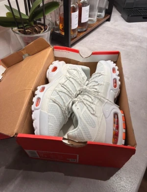 Vita Nike Tn sneakers - Nike Tn sneakers i fräsch vit färg med orange detaljer i sulan. Ovandelen är tillverkad i mesh och syntet med coola linjer och snörning. Sulan har synliga Air-enheter och en chunky look som ger extra attityd. Perfekt för dig som gillar sportig och modern stil. Köpte från Nike för ca 1300kr mitt pris 950kr