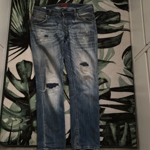 Slim Glenn jeans från Jack & Jones - Snygga blå jeans från Jack & Jones, modell Slim Glenn. De har slitna detaljer och hål på benen för en cool, avslappnad vibe. Klassisk femficksdesign och slim fit som sitter snyggt. Perfekt för dig som gillar streetstyle och vill ha jeans med attityd. Dom har även ett litet hål p jeansen men den är inte så synlig kontakta ifall du vill se