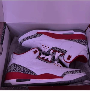 Nike Air Jordan 3 Vit/Röd sneakers - Nike Air Jordan 3 sneakers i vitt och rött med ikoniska elephant print-detaljer i grått och svart. Skorna har snörning, platt sula och rund tå. Ovandelen är tillverkad i skinn med röda inslag runt kragen och sulan. Perfekt för dig som vill sticka ut med klassisk streetstyle. Skickar kvittot vid intresse av köp. Kan även mötas i Stockholm 