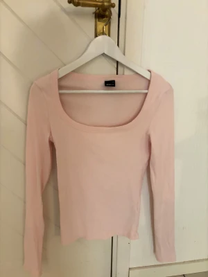 Ljusrosa tröja Ginatricot - Säljer en ljusrosa långärmad ribbad topp från Ginatricot med rundad, bred urringning. Tunn och mjuk i bomullsmaterial. Använd 2-3 gånger. 