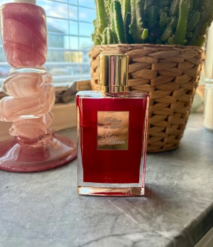 Kilian Rolling in Love parfym - Snygg och lyxig parfym från Kilian med röd flaska och gulddetaljer. Perfekt för dig som vill sticka ut och addera en exklusiv touch till din stil. Namnet 'Rolling in Love' syns tydligt på flaskan. 50 ml men använd, se andra bilden för hur mycket som är kvar 