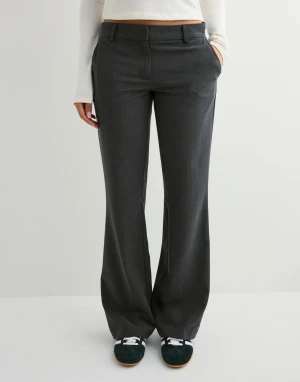 Mörkgrå kostymbyxor med flare fit  - Snygga mörkgrå kostymbyxor med vida ben och klassisk passform. Byxorna har hällor för bälte, diskreta fickor fram och bak samt stängs med dragkedja och knapp. Perfekta för en clean och stilren look.