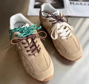 Miu Miu sneakers i beige mocka - (35-44) Snygga sneakers från Miu Miu i beige mocka med kontrasterande snörning i grönt, vitt och brunt. Modellen har rund tå, platt sula och vita detaljer på plösen med Miu Miu-logga. Finns även i grått och mörkbrunt med olika färger på snörena. Perfekt för dig som gillar att sticka ut med dina skor.