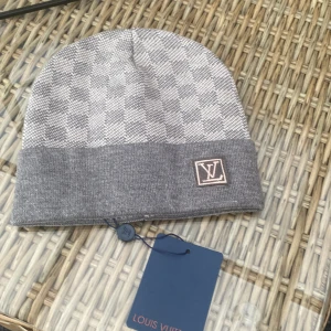 Grå stickad mössa med logo  - Snygg grå mössa i bra skick. Använd få gånger. Passar till både vardagsbruk och kalla dagar.