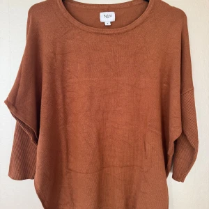 Brun stickad tröja från Saint Tropez - Brun eller snarare kamelfärgad tröja i viskos från Saint Tropez. Tröjan har rund halsringning, ribbade ärmar och en loose passform. Passar både till jeans och kjol.