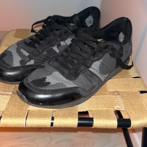Valentino rockrunners - Säljer ett par svarta och grå sneakers med coolt mönster och meshdetaljer. Skorna har snörning och platt sula, samt detaljer i mocka och syntet. Perfekta för dig som gillar en sportig och urban stil. Storlek 44 använda 2 gånger den februari 
