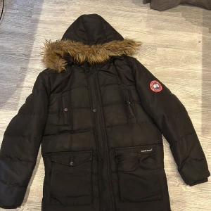 Svart dunjacka från Canada Goose - Svart dunjacka från Canada Goose med pälsluva, ena knappen där uppe och där nere är borta men gå ändå stänga. De är bud så den med högst pris får den börja på 800 kr. Bytes kan tas! Storlek L men passar M 