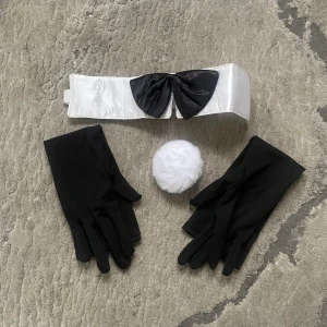 Svarta handskar till bunny-outfit - Svarta, släta handskar i syntetmaterial som ingår i en bunny-kostym. Setet inkluderar även en vit satinliknande krage med svart rosett och en fluffig vit svans i fuskpäls. Perfekt för temakvällar eller maskerad.