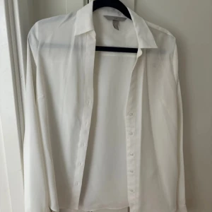 Vit skjorta från H&M i storlek 32 - Vit skjorta/blus från H&M i storlek 32. Skjortan har lång ärm, krage och knäppning framtill. 
