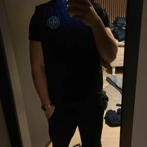 Svart väst från Stone Island - Svart väst från Stone Island med klassisk logga på bröstet. Västen är skön och stilren.