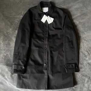 Svart rock från Bläck - Stilren svart rock från Bläck med klassisk krage, knäppning framtill och sidofickor. Jackan är helt ny aldrig använd, prislapparna sitter kvar. Nypris ”1999kr”. Vid frågor och funderingar tveka inte på att höra av dig!