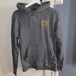 Grå Morris hoodie - Grå hoodie från Morris med fickor framtill och märke på bröstet.