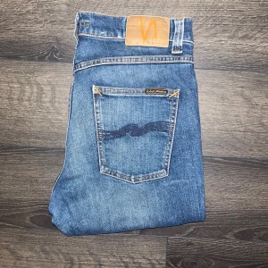Nudie jeans Lean Dean  - Snygga blå  jeans från Nudie Jeans med klassisk femficksdesign och coola kontrastsömmar. Jeansen har en mörkblå tvätt med slitningar och är tillverkade i 99% ekologisk bomull och 1% elastan. Modell Lean Dean. Midja 39cm, längd 105cm. JAG SKICKAR EJ FLER BILDER NÄR JAG BÄR JEANSEN! för storleksguide hänvisar jag till måtten och för bättre inblick i passformen rekommenderar jag att googla på modellnamnet :) s3