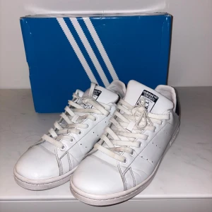 Stan Smith blåa - Klassiska Adidas Stan Smith sneakers i vitt skinn med marinblå accenter. Skorna är använda men bra omhändertagna och väldigt välvårdade. Har behållt sin färg ytterst bra.