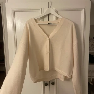 Beige kofta från & Other Stories - Superfin beige kofta från & Other Stories i stickad bomullsmix. Modellen är croppad med v-ringning, långa ärmar och knappar framtill. Perfekt för lager-på-lager och enkel att styla till olika looks.