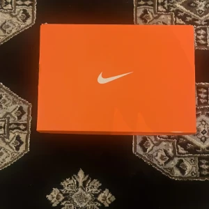 Svarta Nike fotbollsskor med snörning - Säljer ett par svarta Nike fotbollsskor med snygg, modern design och snörning. Skorna har en strömlinjeformad form, platt sula med dobbar och diskret Nike-logga på sidan. Perfekta för dig som vill ha stilrena och funktionella skor på planen.