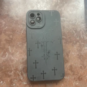 iPhone 11Pro Max Skal Svart med Korsmönster - Stilrent svart skal med korsmönster, designat för iPhone 11 Pro Max. Skalet har exakta utskärningar för kamera och portar. Viss smuts och lätt slitage syns, men inga sprickor eller större skador. Perfekt för dig som vill skydda din mobil med unik stil.