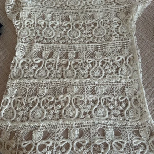 Vit spetskompetens med kort ärm - Superfin vit spetstop med korta ärmar och detaljerat broderat mönster. Toppen har en genombruten design med snygga spetsdetaljer och rund hals. Perfekt för dig som gillar boho-vibe och vill sticka ut med coola detaljer.