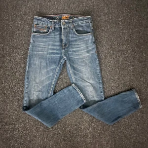 Blå jeans från Pace med broderade fickor - Snygga blå jeans från Pace med klassisk femficksdesign och coola broderade detaljer på bakfickorna. Jeansen har normal passform, raka ben och är tillverkade i slitstarkt denim med ljus tvätt och kontrastsömmar. Lite sönder på läder dekalen backtill men inget märkvärdigt i överigt