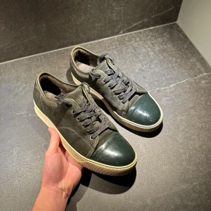 Svarta sneakers med gröna detaljer - Hejsan! Jag säljer nu dessa riktigt feta skor ifrån lanvin. Dem är i storlek uk6 vilket motsvarar ungefär 40-41! Dem är i helt okej skick men inte de bästa! Hör av er om ni har frågor!😃