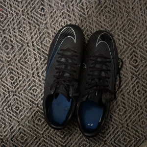 Nike svart-blå fotbollsskor Air Zoom - Säljer ett par svarta Nike Air Zoom fotbollsskor med blå och vita detaljer. Skorna sälj för att de har blivit för små, finns två svarta fläckar på boten av skon men ingen som märks av.
