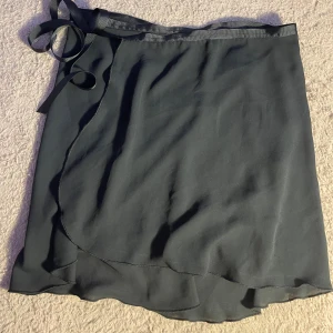 Svart omlott kjol - Fin svart omlottkjol med sidenband i midjan – ger en feminin och elegant look. Lätt, luftig och bekväm att bära. Storlek: S/M Fint skick ✨ 💬 Pris kan diskuteras!  🖤 Passar både till vardag, dejt eller fest!