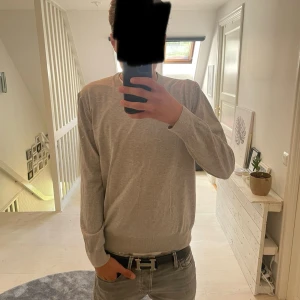 Grå stickad tröja från Hugo Boss - Snygg grå stickad tröja från Hugo Boss i italienskt garn. Enkel och stilren design med rund halsringning och långa ärmar. Perfekt till jeans eller chinos för en clean look.