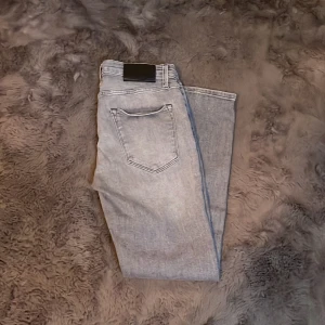 Ljusgrå jeans från Jack & Jones 29/30 - Säljer ett par ljusgrå jeans från Jack & Jones i storlek 29/30. Jeansen har klassisk femficksdesign, raka ben och normal passform. Tillverkade i mjukt denimtyg som är skönt att bära hela dagen. Perfekta för dig som gillar en clean och stilren look.