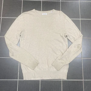 Beige stickad tröja Jack & Jones XS - Beige stickad tröja från Jack & Jones i storlek XS. Enkel och clean design med rund halsringning och ribbade muddar vid ärmslut och nederkant. Perfekt för lager-på-lager och chill vibes.