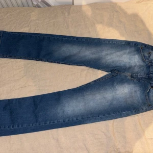 Levi's 511 Skinny jeans blå - Säljer ett par klassiska Levi's 511 Skinny jeans i mellanblå tvätt med snygga slitningar. Jeansen har fem fickor, normalhög midja och raka ben med smal passform. Perfekta för dig som gillar en tidlös och clean look.