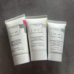 Symbiosis London hudvårdsset - Set med tre vita tuber från Symbiosis London: Radiance Enhancing Hand Spa Treatment (ros + mjölksyra, 50 ml), Enlightening & Exfoliating Cleansing Gel (vit pion + peelmoist, 50 ml) och Revitalising & Redensifying Facial Serum (prebiotika + retinoider, 30 ml). Perfekt för dig som vill boosta din hudvårdsrutin.