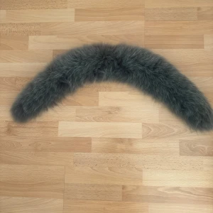 Mörkgrå fluffig pälshalsduk - Säljer en snygg och supermjuk mörkgrå pälshalsduk/krage med clips i ändarna för enkel fastsättning. Perfekt för att ge din outfit en lyxig touch och hålla dig varm under kyliga dagar. Halsduken har en böjd form och är riktigt fluffig och stilren. Med foder.