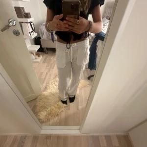 Vita linnebyxor med snörning - Säljer ett par vita linnebyxor med bred resår i midjan och snörning framtill. Byxorna har raka ben, stora fickor både fram och bak och är tillverkade i ett luftigt linnematerial. Perfekta för varma dagar och chill vibes.