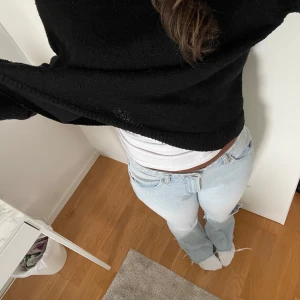 Ljusblå bootcut jeans från Zara - Säljer dessa ljusblå  bootcut jeans från Zara med slitna kanter nertill. Jeansen har låg midja och ett stort hål på ena benet.