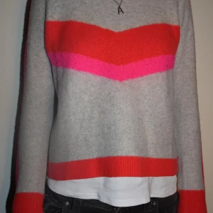 From future tröja  - Snygg stickad tröja i ljusgrått med breda ränder i rött och rosa över bröstet och längs ärmarna. Tröjan har ribbade muddar och neder. Från from future. Och passa S/XS 💗